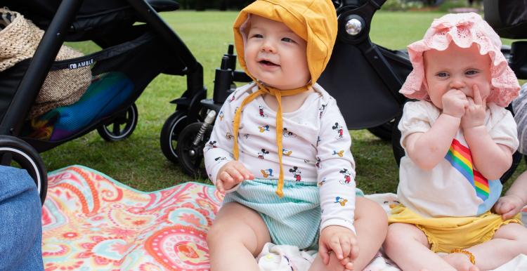 Two babies sitting on a rug