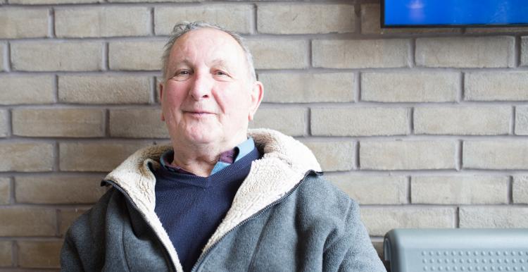 Older man sitting by wall