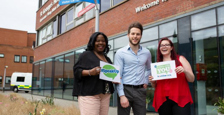 Three people standing outside a hospital encouraging people to speak to Healthwatch