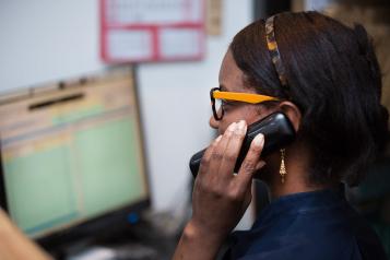Person on the telephone with computer in background