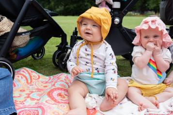 Two babies sitting on a rug