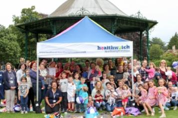 a group picture of all the attendees of the breastfeeding picnic under a Healthwatch gazebo