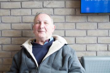 Older man sitting by wall