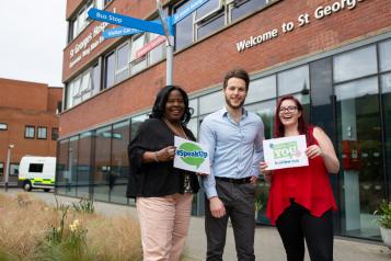 Three people standing outside a hospital encouraging people to speak to Healthwatch