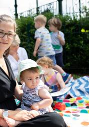 Woman sitting on a picnic blanket with her baby