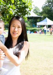 Mother holding baby standing in a park 